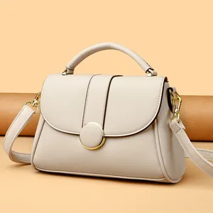 Beige faux leather handbag with gold round buckle and adjustable shoulder strap