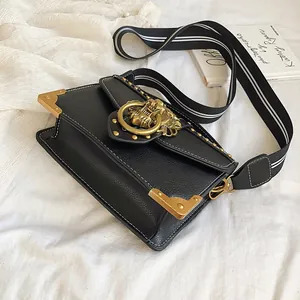 Vintage black square bag with lion head emblem and striped canvas strap on white fabric