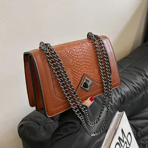 Sac à bandoulière marron texture crocodile avec chaîne et fermoir rotatif métallique