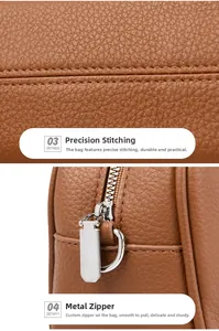 Close-up of brown leather tote featuring precise stitching and silver metal zipper detail
