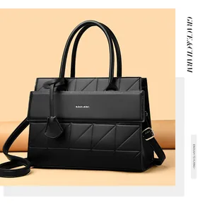Detail of black tote bag with geometric quilted pattern and cylindrical top handles