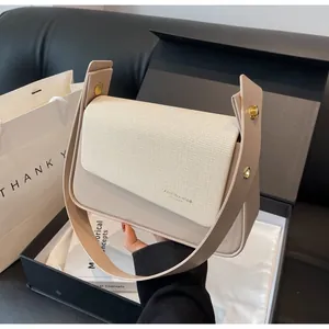 Detail of beige quilted shoulder bag with gold clasp shown with premium gift packaging