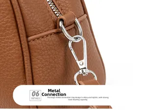Detail of silver hardware lobster clasp and pebble leather texture on a brown Boston bag