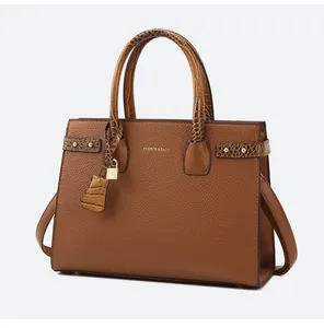 Dettaglio borsa tote in pelle marrone con manici coccodrillo e lucchetto dorato