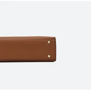 Dettaglio della base della borsa in pelle marrone con piedini dorati e cuciture rifinite