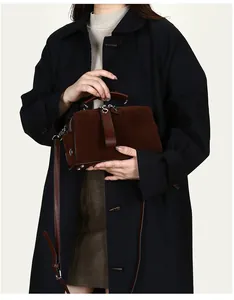 Detail der dunkelbraunen Boston-Tasche aus Wildleder und Leder mit Riemen am Modell