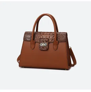 Nahaufnahme der braunen Krokodil-Textur und des Metall-Drehverschlusses der Handtasche