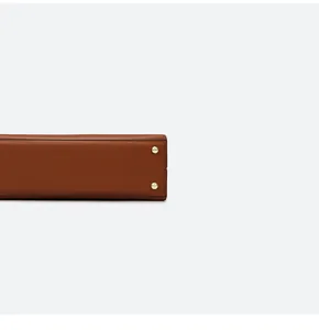 Detailansicht des braunen Taschenbodens mit schützenden goldenen Metallfüßen aus Leder