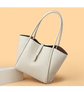 Detail of cream white bucket bag with pebble leather texture and gold buckle on props