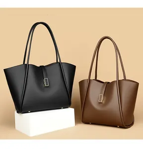 Detail view of large PU leather tote bags in black and dark brown with gold metal accents