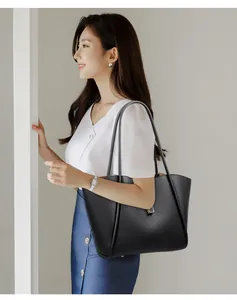 Detailed view of black litchi pattern bucket bag styled on a model in a minimalist setting