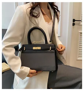 Detailed view of the black leather textured handbag with gold hardware and top handle