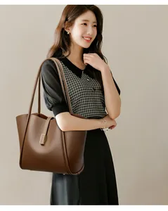 Detail of dark brown tote bag featuring lychee grain texture and gold buckle accents