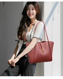 Detail view of burgundy leather tote bag with gold hardware on a female model