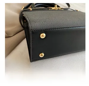Detailed view of durable handbag bottom with four protective gold metal feet studs