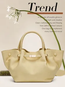 Detail of cream yellow leather tote bag with lychee texture and gold-tone metal hardware