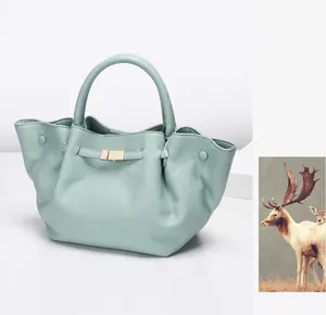 Detail of mint blue tote bag featuring lychee grain leather and gold metal buckle