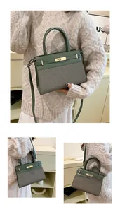 Detail view of two-tone green and grey leather handbag with metal turn-lock closure