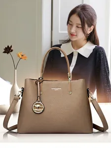 Detalle de bolso en cuero granulado caqui con logo metálico y colgante de canguro