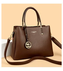 Detalle de bolso de cuero granulado con logo dorado y accesorio de dije de canguro