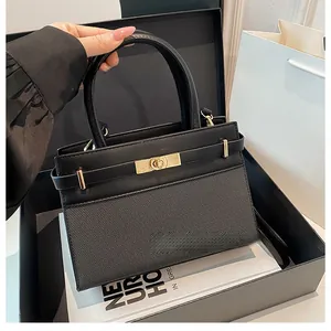 Detail of elegant black handbag with metallic gold clasp and premium mixed textures