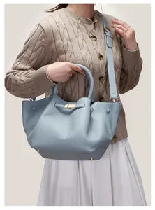 Close-up of light blue winged tote bag showing lychee leather texture and gold hardware