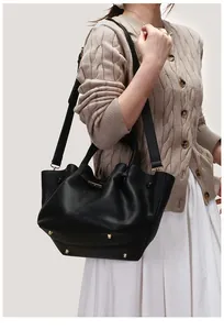 Close-up of black lychee-grain leather tote bag with protective gold studs and metal buckles