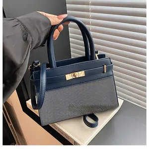 Close-up of navy leather and grey striped fabric handbag with golden metal twist lock