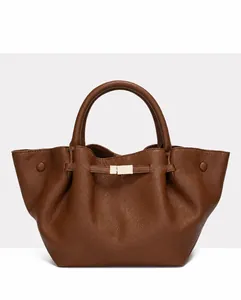 Macro detail of dark brown litchi pattern leather tote bag with gold metal buckle