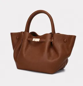Detail showing pebbled leather texture and gold buckle on a brown tote bag