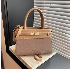 Detail of earth-tone handbag with woven texture and gold twist-lock closure