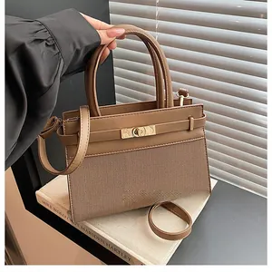 Detail of stylish brown woven patchwork handbag with gold-tone twist lock closure