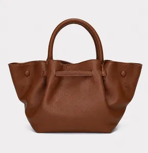 Close-up of caramel leather tote with lychee grain texture and winged design details