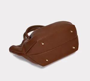 Detailed view of the brown lychee leather tote bag bottom with protective gold metal studs