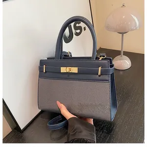 Detail of dark blue handbag featuring mixed textures and golden rectangular metal clasp