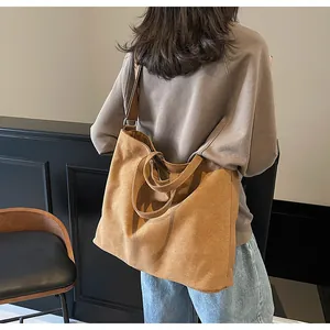 Bolso tote de lona marrón llevado al hombro por una modelo en un interior minimalista