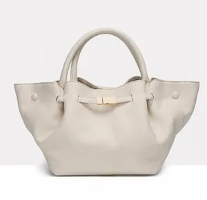 Close-up of beige litchi grain tote bag with gold metal clasp and wing design