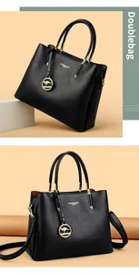 Detalle de bolso negro con textura de lichi, herrajes dorados y colgante de canguro
