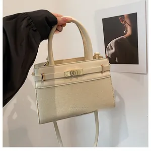Detail of cream white handbag featuring a mix of smooth leather and woven textures with gold lock