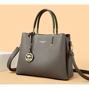 Detalle de bolso de mano gris oscuro en cuero granulado con colgante de canguro dorado