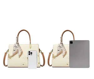 Sac fourre-tout avec broderie papillon montré à côté d'un iPad pour l'échelle