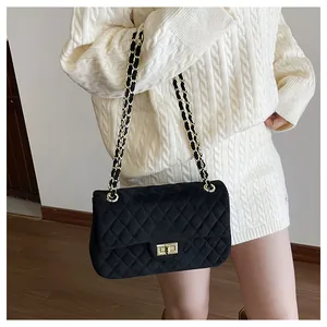 Close-up of black velvet quilted crossbody bag with gold chain strap and metal clasp
