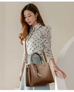 Bolso de mano marrón en cuero granulado con colgante de canguro dorado y asa suave