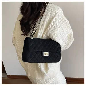 Detail of black quilted velvet chain bag worn by model, showing its size and texture