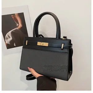 Detail of black crossbody bag featuring textured fabric panels and golden metal buckle