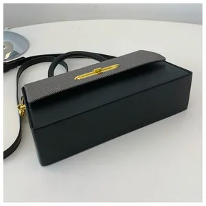 Detailansicht einer zweifarbigen Handtasche mit grauer Stoffklappe und goldenem Schloss