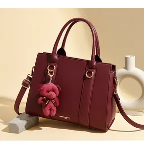Détails du sac cabas bordeaux en cuir avec lettrage doré et charme d'ours en peluche