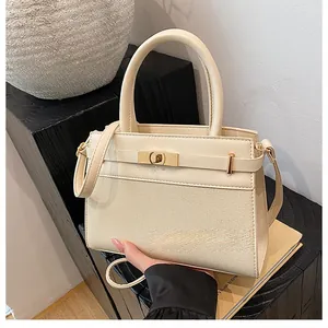 Detail of beige textured handbag with gold metal twist lock and woven leather finish