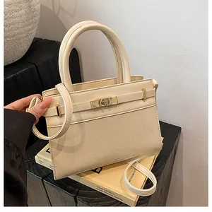 Detail view of cream leather handbag with metallic clasp lock and textured finish