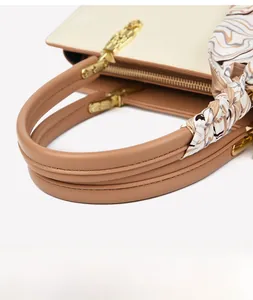 Détail du sac cabas bicolore avec ferrures dorées et poignée ornée d'un foulard en soie